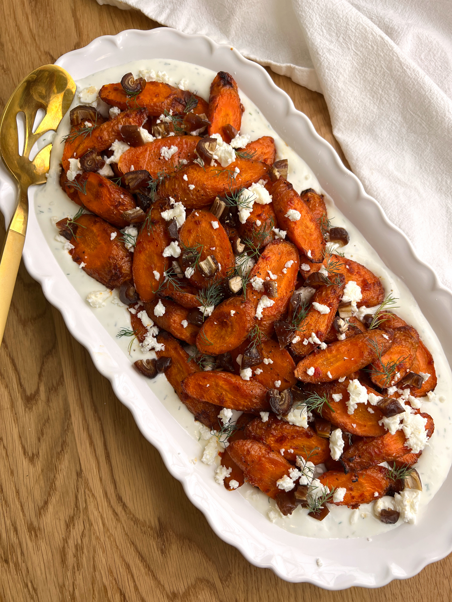 Harissa Maple Carrots with Whipped Feta on White Platter with Gold Serving Spoon