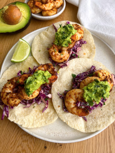 3 air fryer shrimp tacos with cilantro lime slaw on a white plate with lime wedge