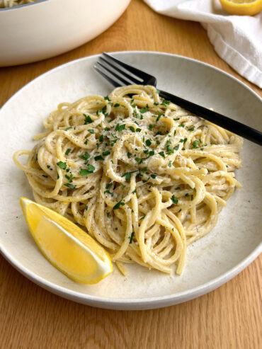 Lemon Pepper Pasta topped with parsley and a lemon wedge on the side