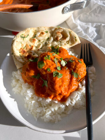 dairy free butter chicken meatballs served with white rice, cilantro and naan on white plate with black fork
