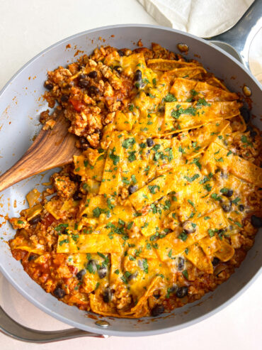 the best ground turkey enchilada skillet in pan with wooden spatula taking a scoop out