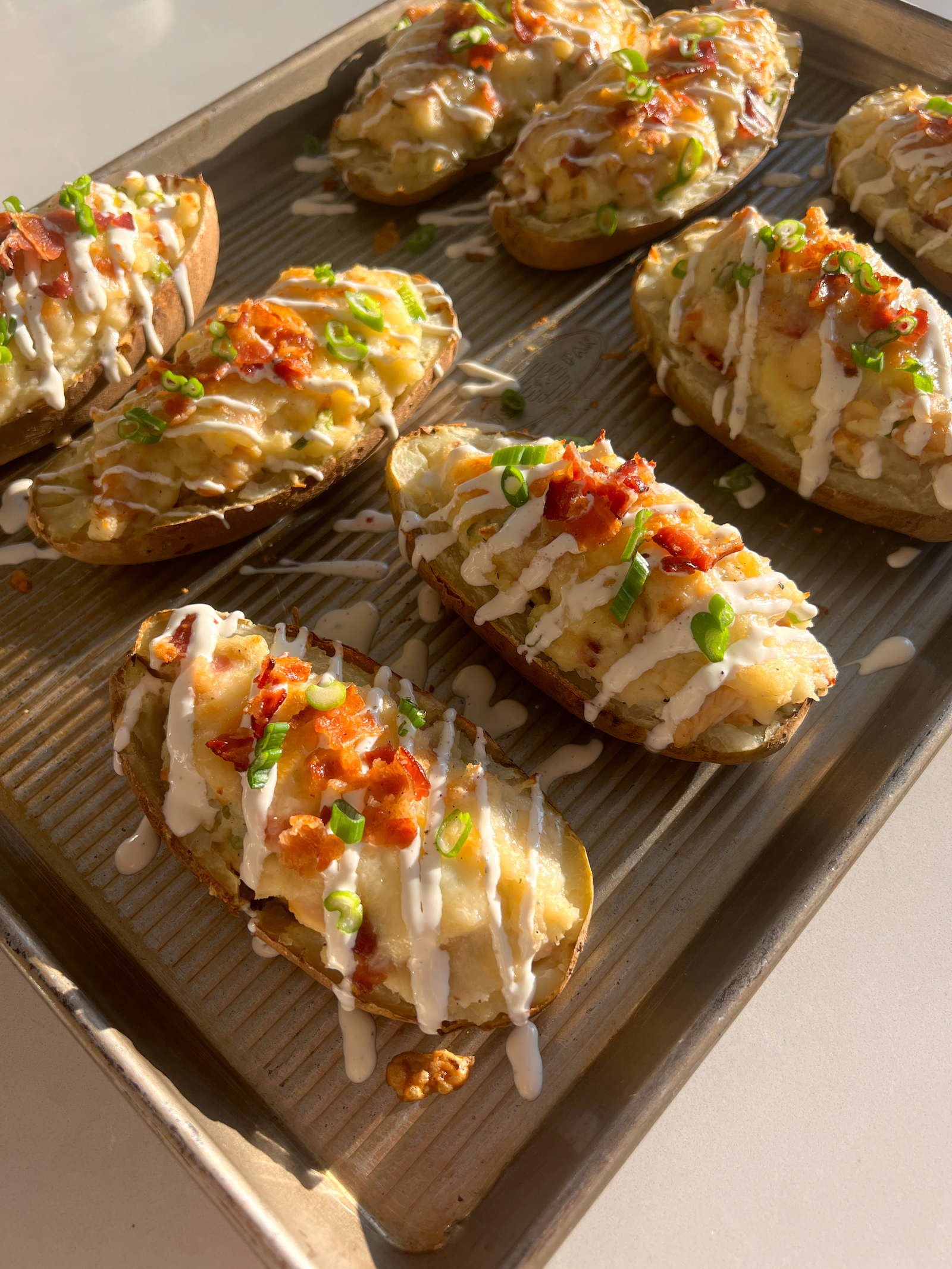 Chicken Bacon Ranch Twice-Baked Potatoes on baking sheet with garnishes