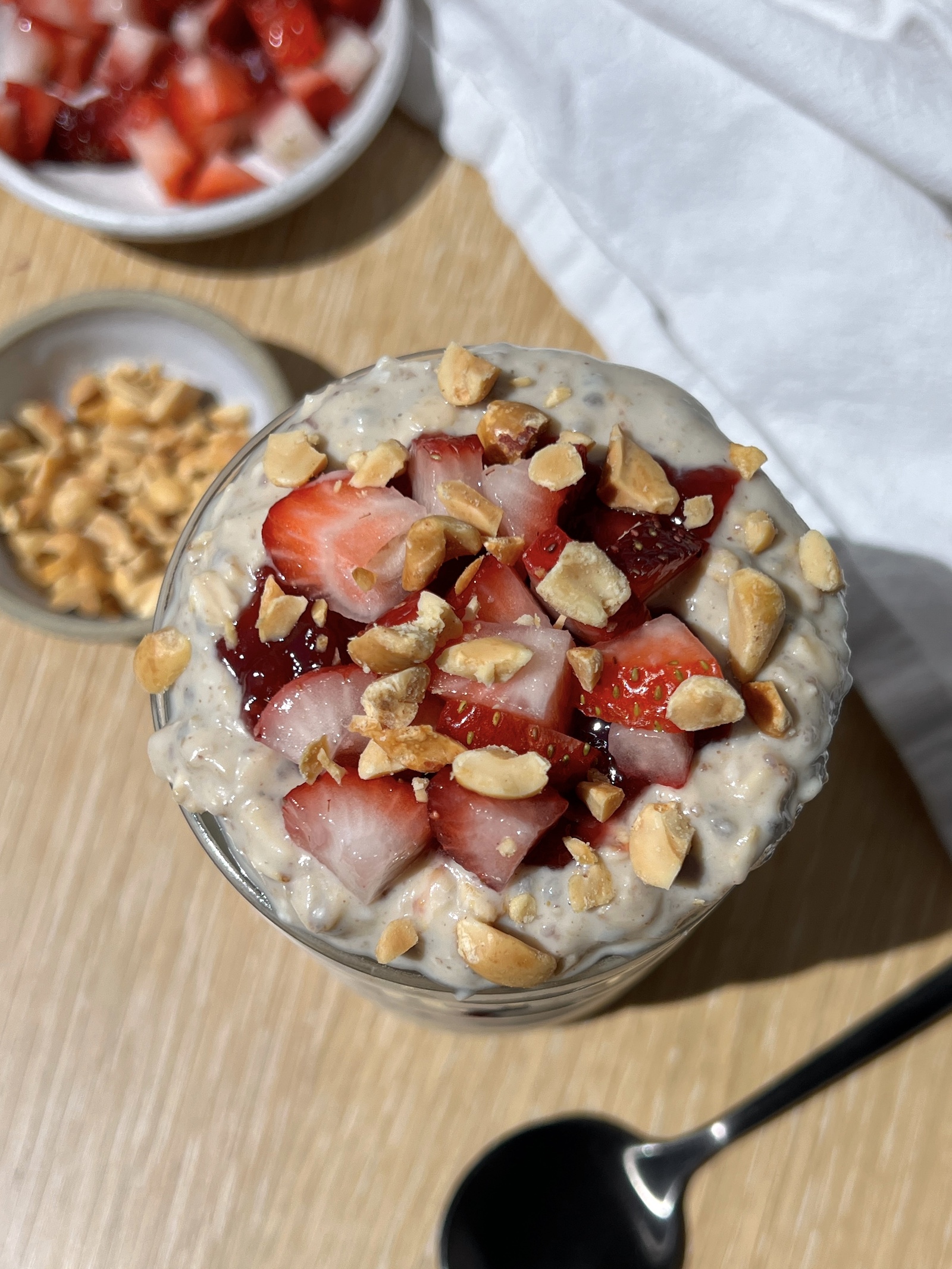 overhead view of high-protein peanut butter and jelly overnight oats in a glass jar topped with strawberries and peanuts