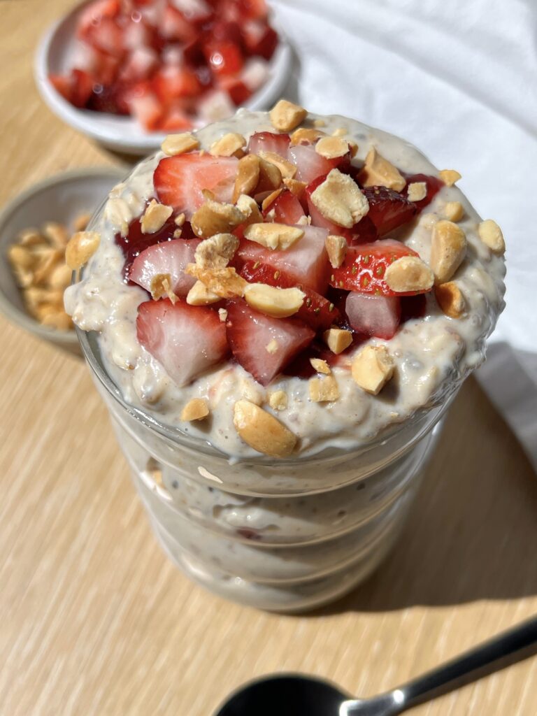 high-protein peanut butter and jelly overnight oats in a glass jar topped with strawberries and peanuts