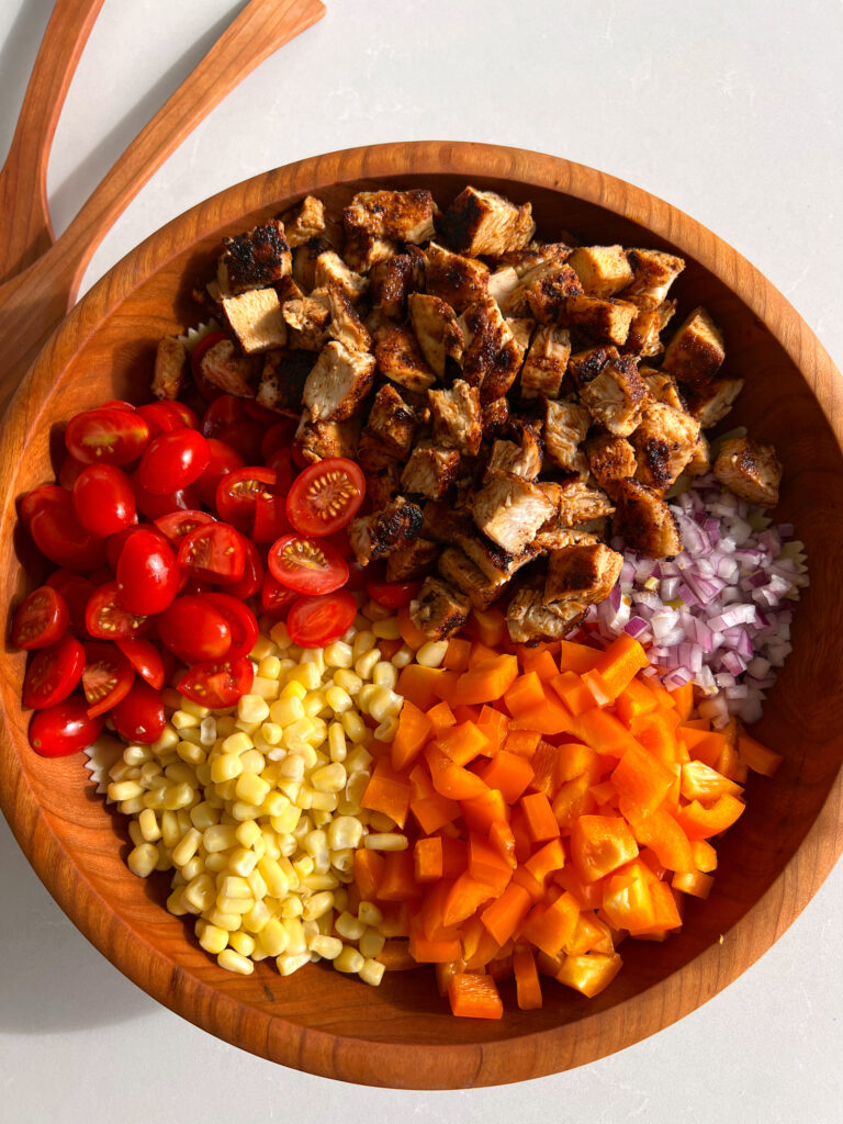 components of cilantro lime pasta salad with chipotle chicken in wooden salad bowl