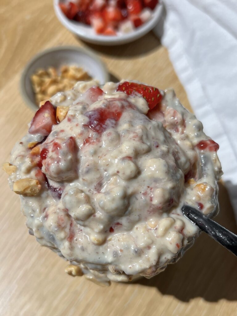 high-protein peanut butter and jelly overnight oats with black spoon taking a bite out