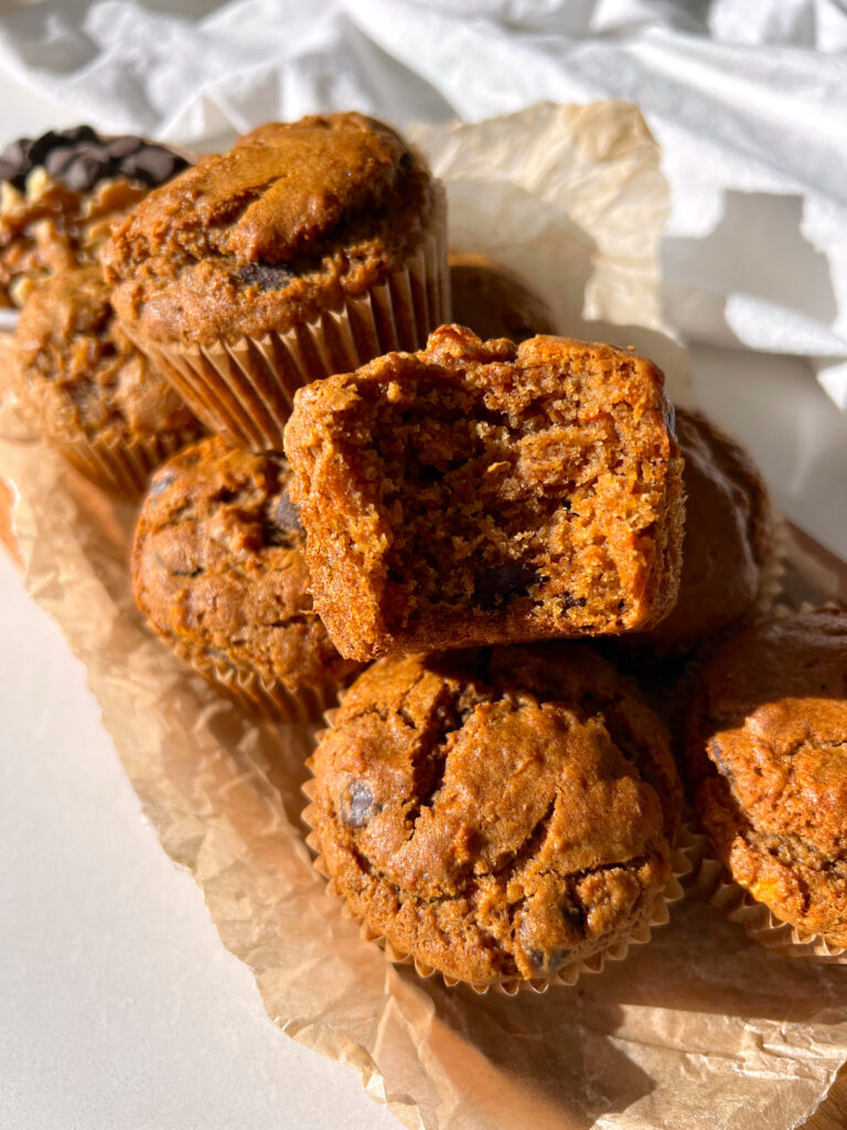Gluten Free Carrot Cake Muffins with Chocolate Chips stacked on top of each other with a bite taken out