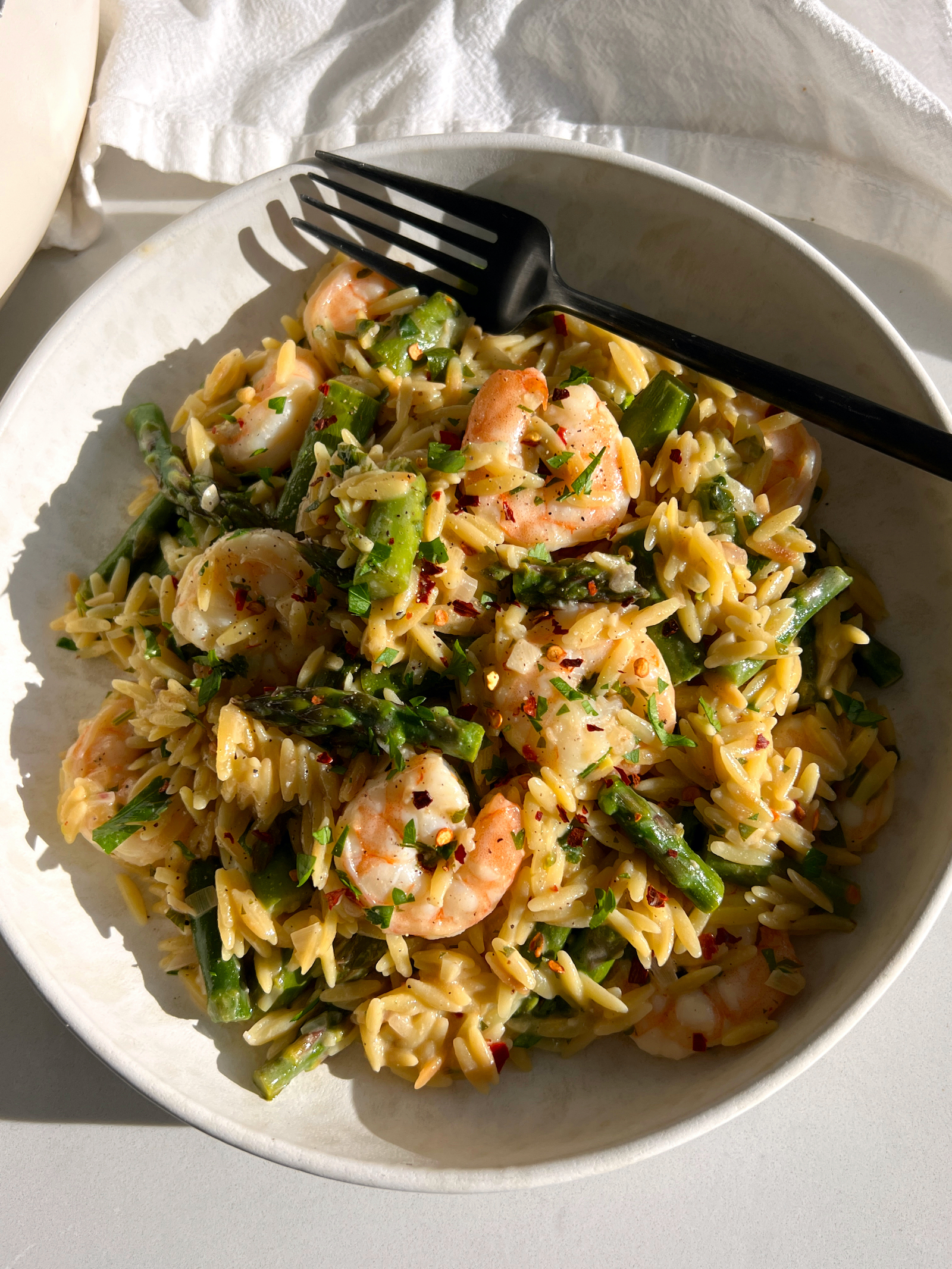 Creamy Shrimp Scampi with Orzo and Asparagus on white plate with black fork