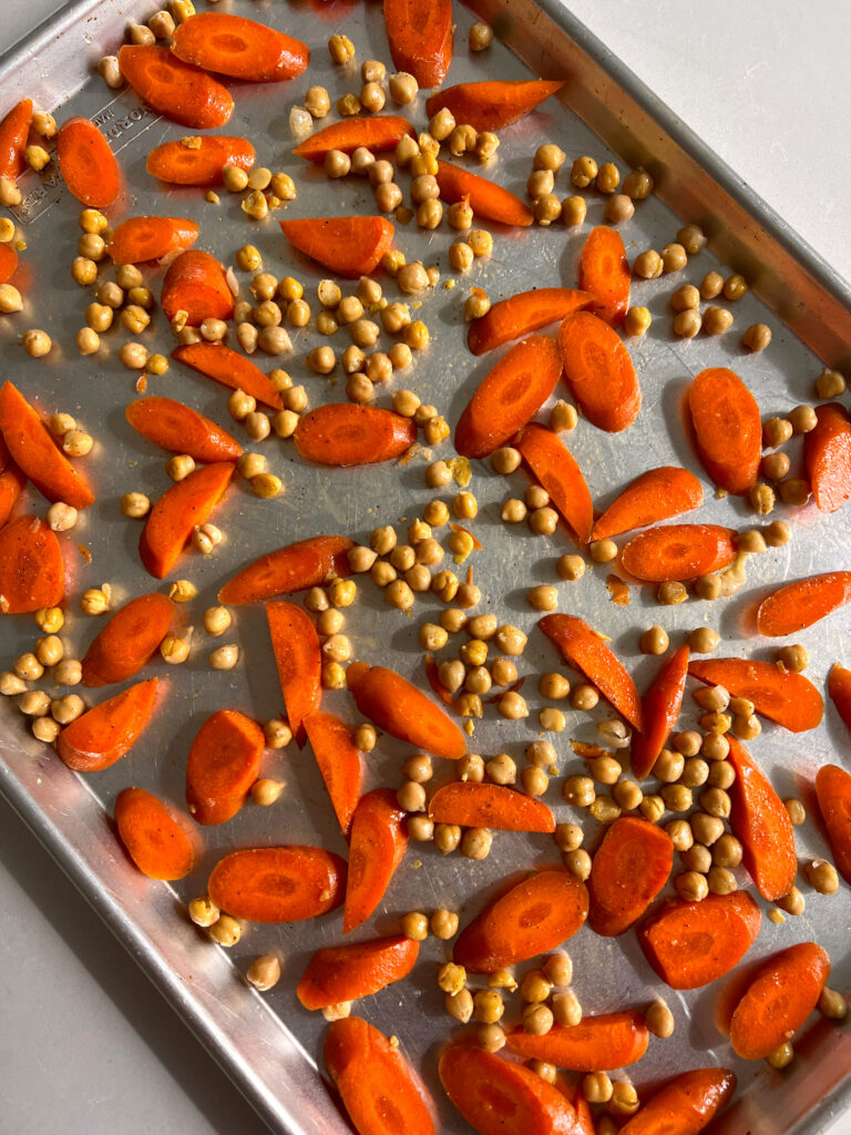 sliced carrots and chickpeas on a baking sheet before being roasted