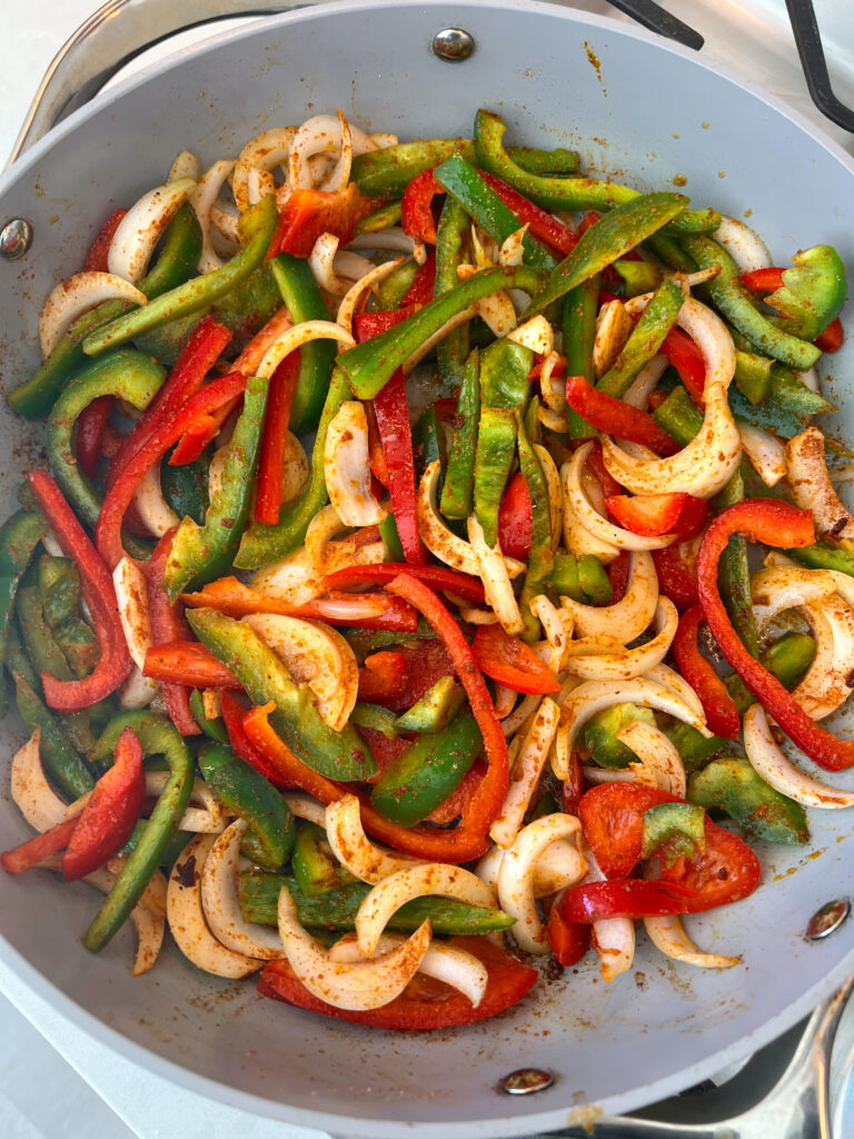 bell peppers and onions sautéing in large pan