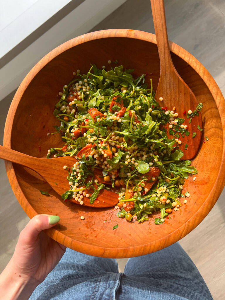 harissa couscous salad with roasted vegetables in wooden salad bowl after being tossed