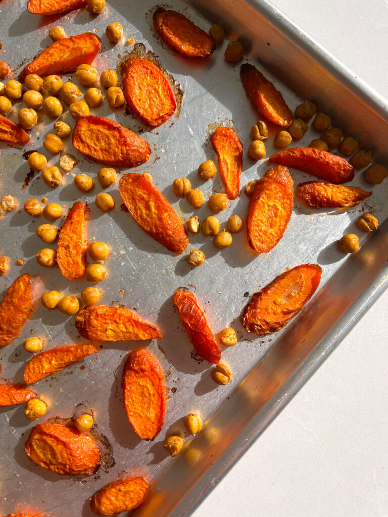 sliced carrots and chickpeas on a baking sheet after being roasted